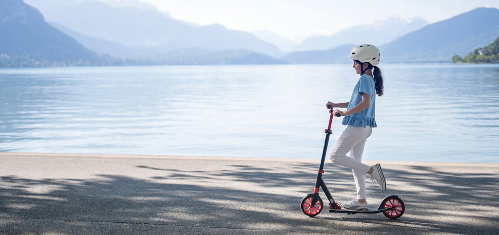 Niña en scooter Globber NL 205 junto al lago
